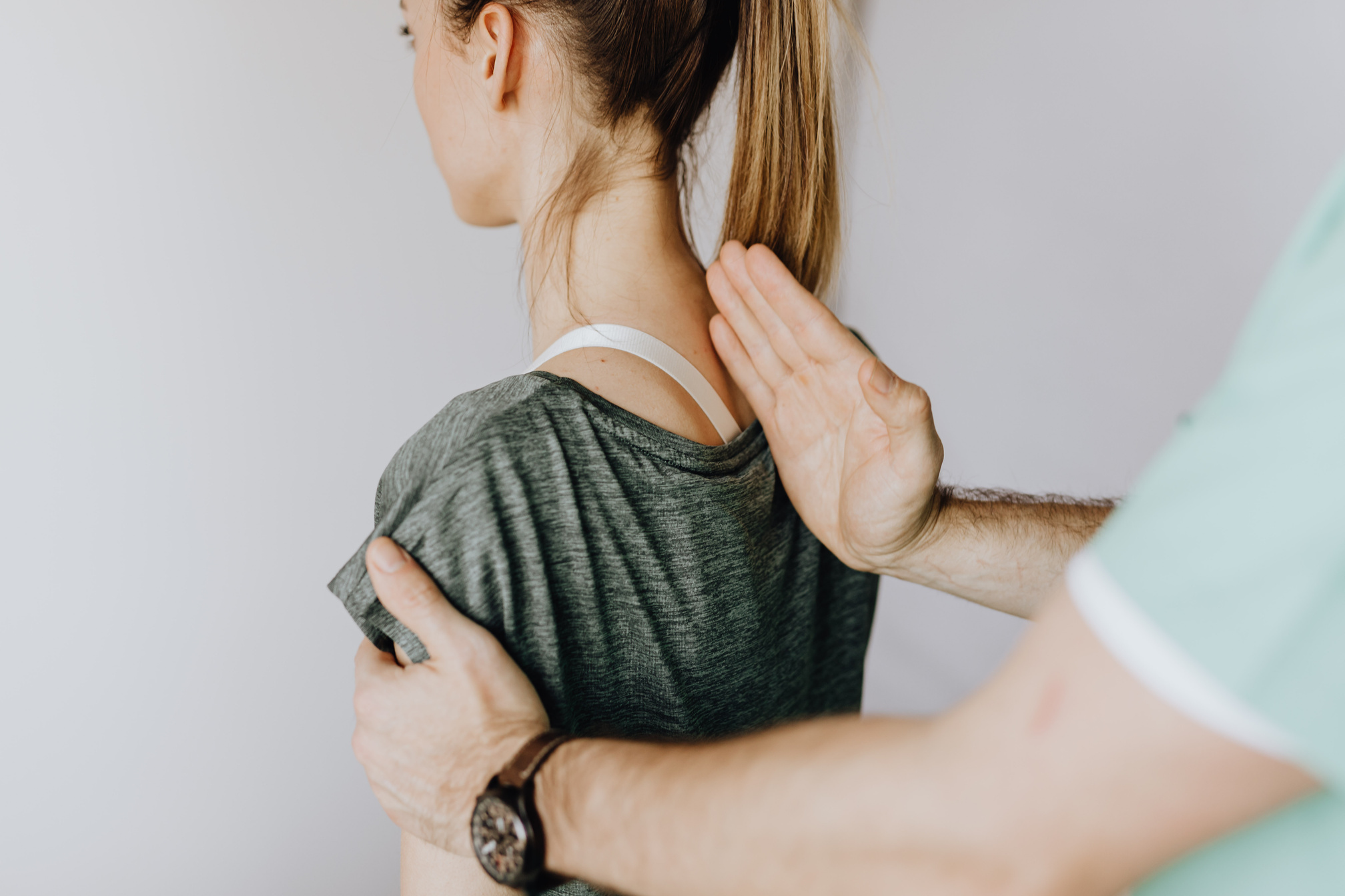 Crop anonymous chiropractor examining spine of fit lady in hospital